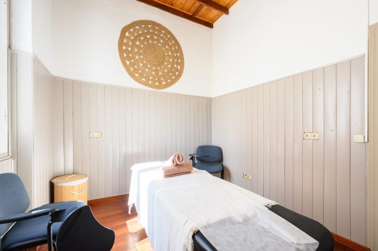 Cabina de prácticas con camilla y silla de pala, iluminada con luz natural