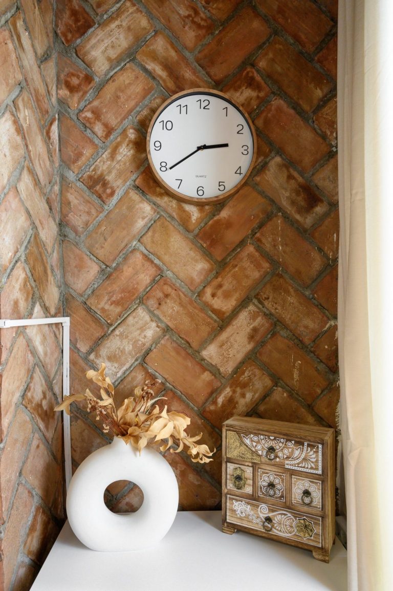 Rincón del aula con reloj sobre pared de ladrillo visto
